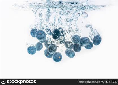 Bunch of delicious looking blueberries splashing into water surface and sinking. Isolated on white background, splash food photography.. Bunch of blueberries splashing into water surface and sinking. Isolated on white background, splash food photography.
