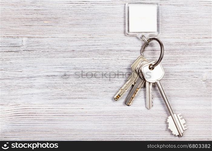 bunch of door keys with white blank key chain on wooden board