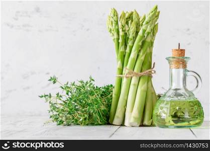 Bunch of fresh asparagus with thyme and bottle of olive oil