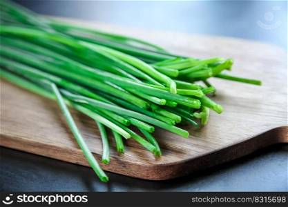 Bunch of fresh chives on a wooden cutting board. Bunch of chives on a wooden cutting board