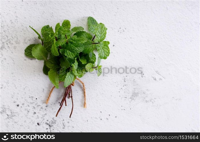 bunch of fresh green mint laves on white marble background. Top view with copy space.