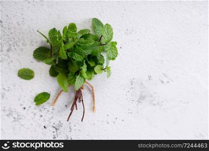 bunch of fresh green mint laves on white marble background. Top view with copy space.