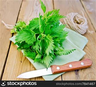 Bunch of fresh green nettle, knife, ball of twine, doily on a wooden boards background