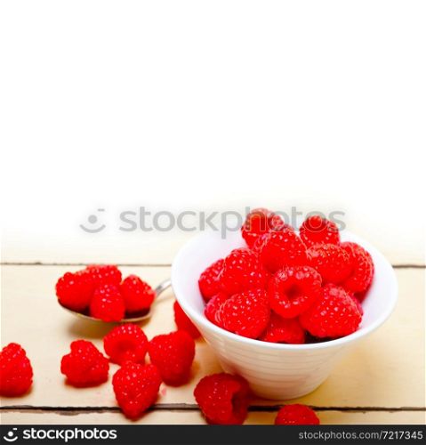 bunch of fresh raspberry on a bowl and white wood rustic table