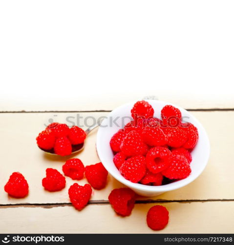 bunch of fresh raspberry on a bowl and white wood rustic table