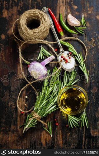 Bunch of fresh rosemary, sult, pepper and olive oil on old wooden table