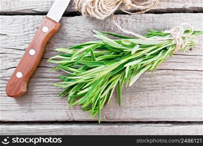 Bunch of fresh rosemary tied with twine, skein of rope and a knife on wooden board background from above