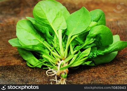 Bunch of fresh spinach with roots over old wooden surface. Dark rustic style.. Bunch of fresh spinach with roots over old wooden surface. Dark rustic style