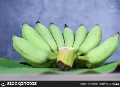 bunch of green banana on raw banana leaf background