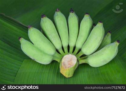 bunch of green banana on raw banana leaf background