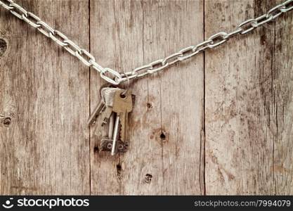 Bunch of keys hanging on chain against old wooden wall