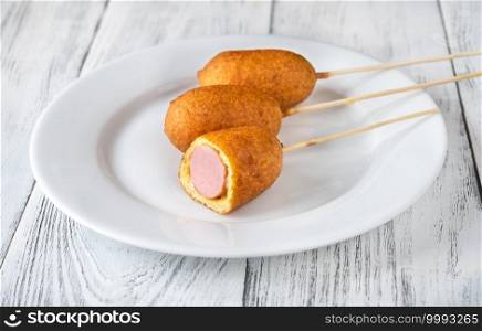 Bunch of mini corn dogs on white serving plate