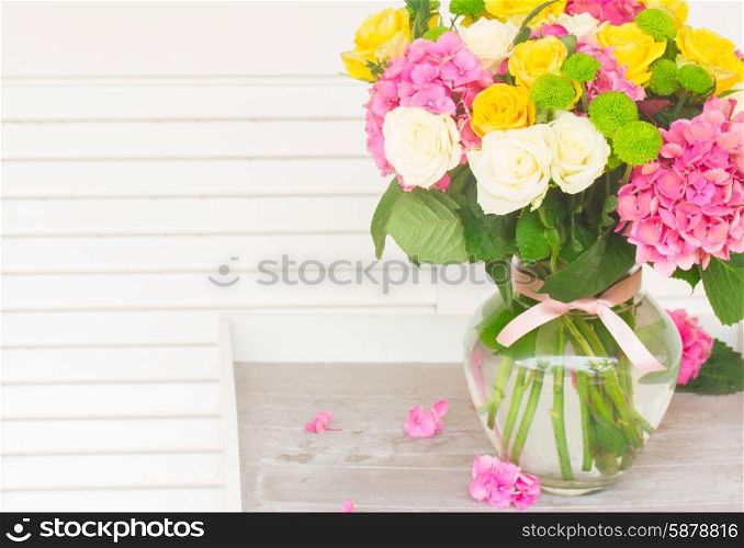 bunch of pink hortensia , yellow and white fresh roses in vase