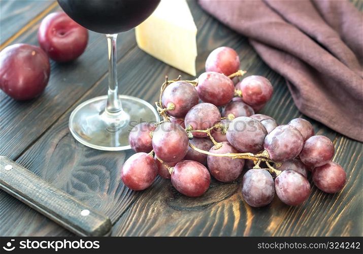 Bunch of red grape with cheese and glass of red wine