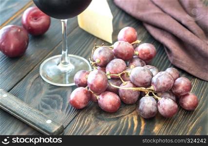 Bunch of red grape with cheese and glass of red wine