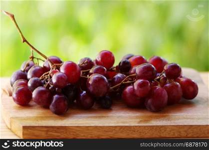 Bunch of red grapes on table, green background