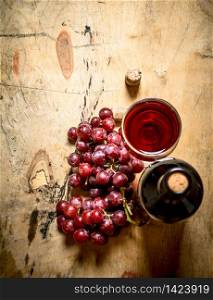 Bunch of red grapes with a bottle of wine. On wooden background.. Bunch red grapes with a bottle of wine.