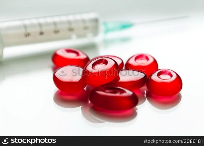 Bunch of red pills & syringe with needle,isolated on white surface with reflection,cure & medication for Coronavirus COVID-19 virus disease,hope & faith in research for vaccine,concept illustration