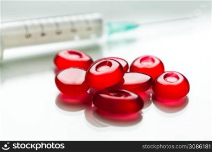 Bunch of red pills & syringe with needle,isolated on white surface with reflection,cure & medication for Coronavirus COVID-19 virus disease,hope & faith in research for vaccine,concept illustration