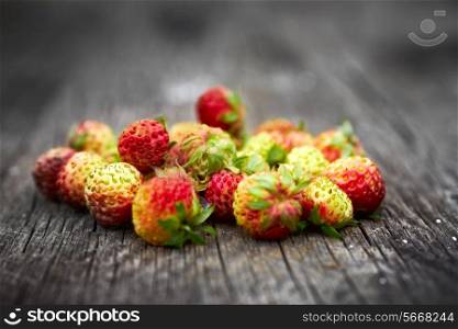Bunch of red wild strawberry on the old wooden background