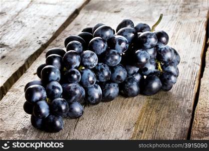 Bunch of ripe juicy blue grapes on a wooden background