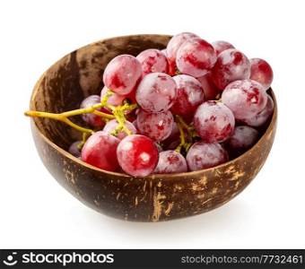 Bunch of ripe red grapes in a coconut bowl on a white background