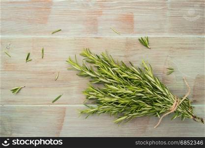 Bunch of rosemary on old wooden board. Top view with copy space