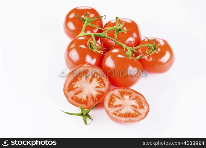 Bunch of tomatoes with two halves over white background