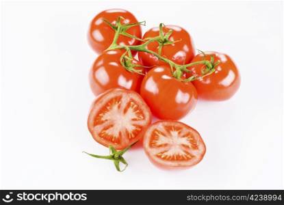 Bunch of tomatoes with two halves over white background