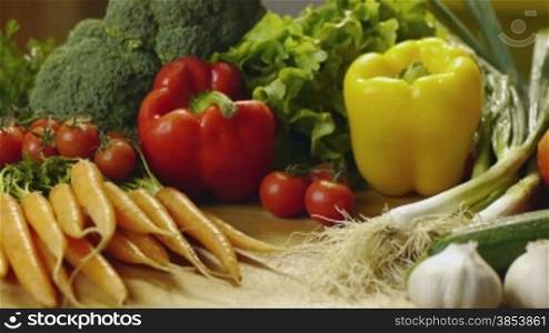 Bunch of wet tomatoes, peppers, carrots, broccoli, garlic and other vegetables on kitchen table. Dolly shot, sequence