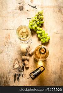 Bunch of white grapes with a bottle of wine, a corkscrew and stoppers. On wooden background.. Bunch of white grapes with a bottle wine