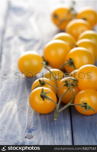 Bunch of yellow cherry tomatoes on wooden table