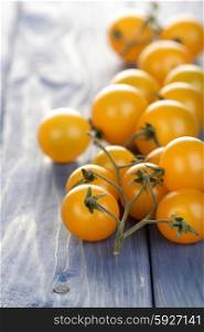 Bunch of yellow cherry tomatoes on wooden table