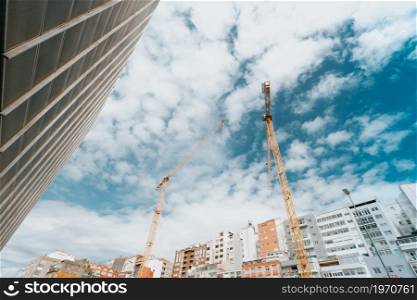 Bunch of yellow cranes on the city under a bright and blue sky with copy space
