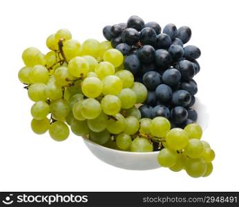 Bunches of black and green grapes in a white cup on a white background, isolated
