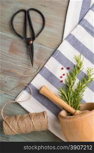 Bunches of rosemary and thyme with old-fashioned scissors. Wood table background.