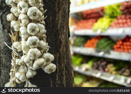 Bundle garlic hung on hang in vegetable market.