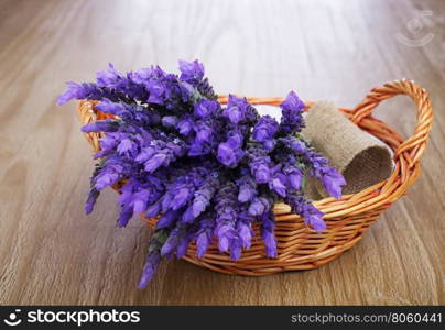 bundle of lavender flowers in wicker basket on vintage wooden table