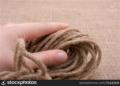 Bundle of linen rope in hand on a brown background