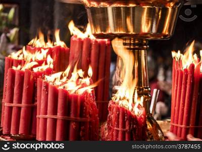 Bundles of red candles, bound with red bands, are burning with bright flames at a Buddhist temple in Taiwan.&#xA;
