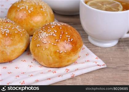 Buns with sesame seeds on a table and a cup of tea