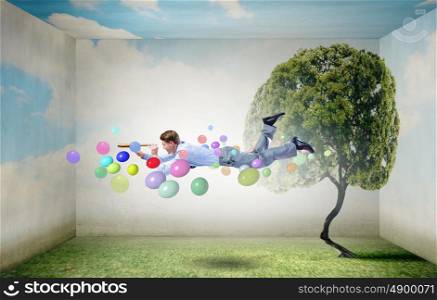 Buoyant and happy. Businessman flying in sky among balloons and looking in spyglass