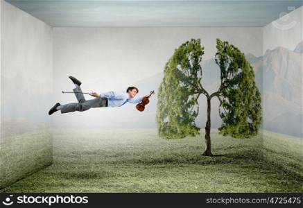 Buoyant and happy. Businessman flying in sky and playing violin