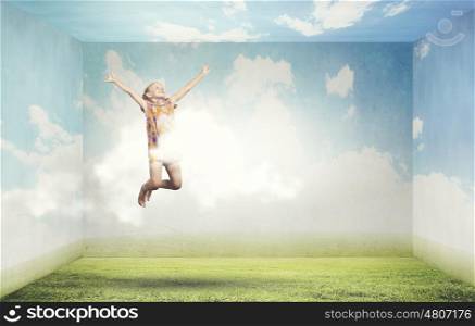 Buoyant and happy. Little cute happy girl jumping high in sky