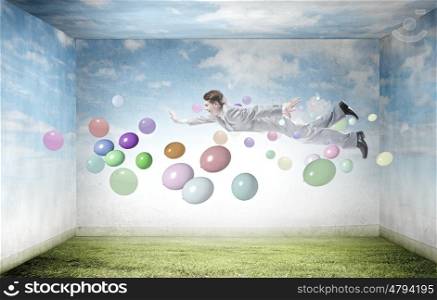 Buoyant and happy. Young man flying in sky among flying around papers