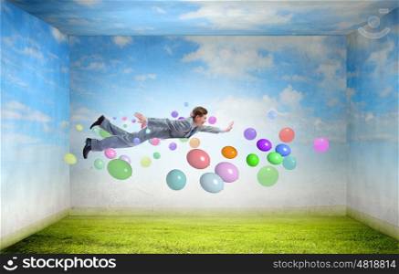 Buoyant and happy. Young man flying in sky among flying around papers