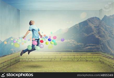 Buoyant and happy. Young man jumping in sky among colorful balloons