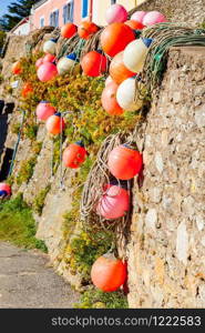 buoys of nets and colorful moorings that dry against a wall in the sun, typical landscape of a fishing port