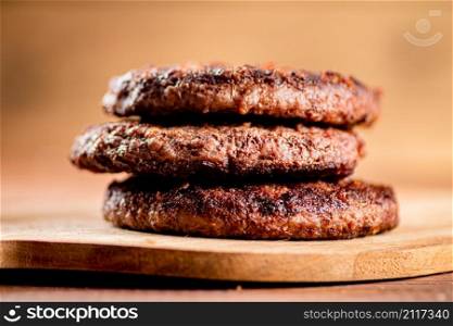 Burger grill on a cutting board. On a wooden background. High quality photo. Burger grill on a cutting board.