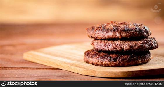 Burger grill on a cutting board. On a wooden background. High quality photo. Burger grill on a cutting board.